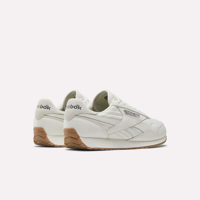 A pair of Women's Classic AZ Shoes by Reebok in white, crafted with a leather upper and a gum sole, displaying the signature Reebok logo on both the side and heel. Presented against a plain white background.