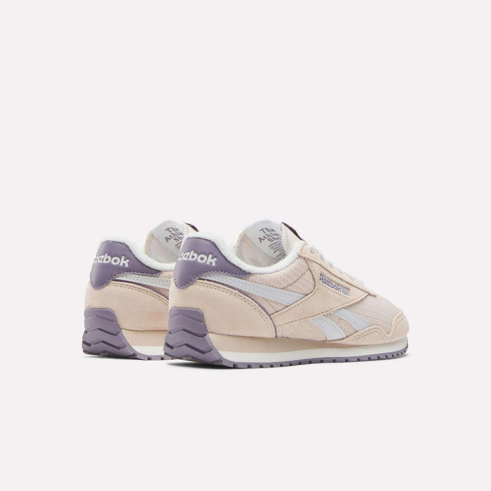 The Women's Classic AZ Shoes by Reebok in light beige with lavender accents, white side stripes, and laces evoke the timeless retro running style of classic 70s sneakers, shown against a plain white background.