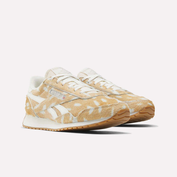 The Women's Classic AZ Shoes by Reebok feature a beige and white suede upper with a fuzzy cow-print pattern, white laces, and a gum rubber sole for retro style—shown here on a plain white background.