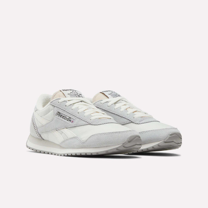 A pair of Reebok Women's Classic AZ Shoes in white and light gray, with suede and mesh accents and a low-profile design, displayed side by side on a plain white background.