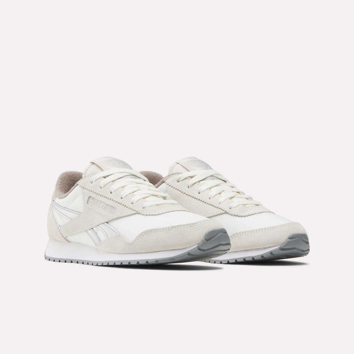 A pair of Reebok Women's Classic AZ Shoes in white and light beige with suede and mesh details, vintage-inspired accents, a low-cut design, white laces, and gray rubber soles displayed on a plain white background.
