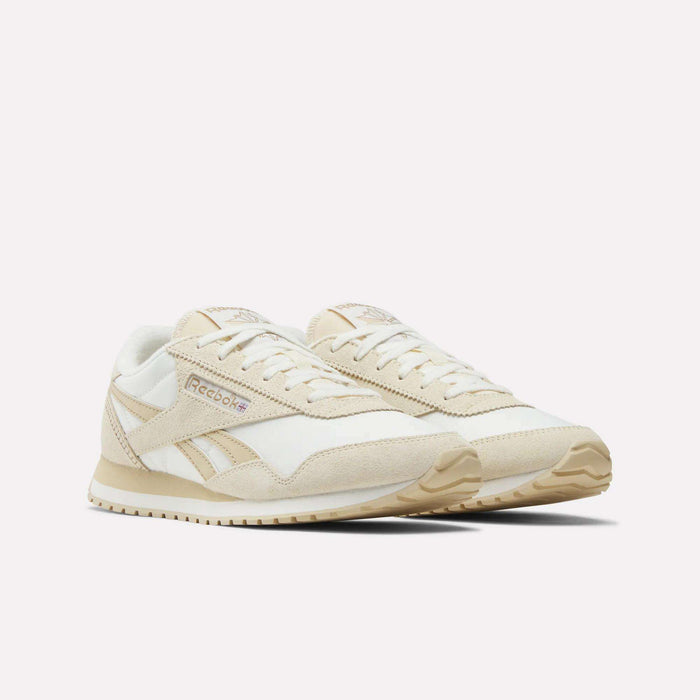 Reebok Women's Classic AZ Shoes in beige and white are shown on a plain white background, featuring a retro low-profile design with suede and mesh panels, beige soles, and Reebok branding on the side.