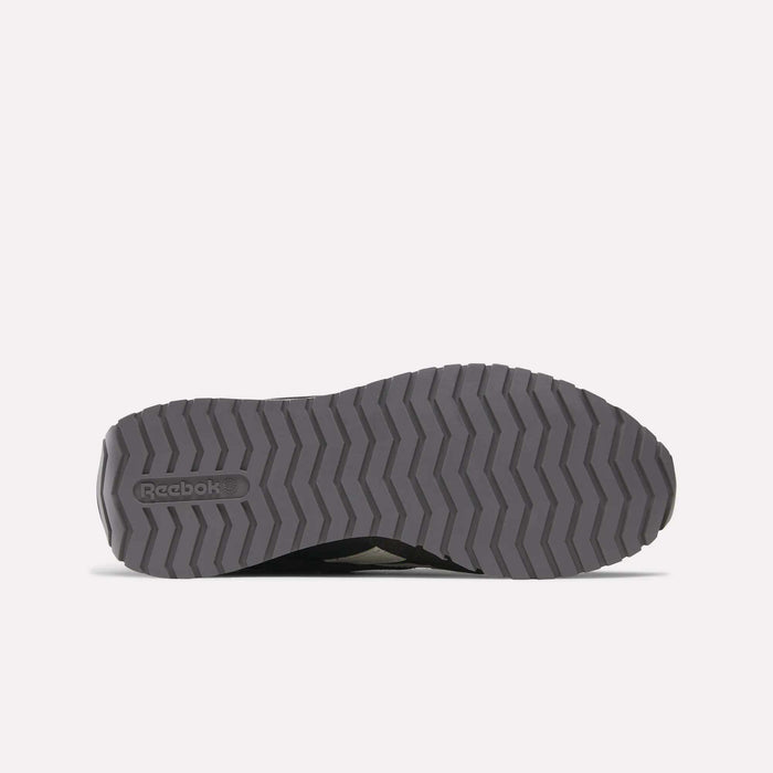 The image displays the bottom view of Reebok Women's Classic AZ Shoes, featuring a gray zigzag-patterned sole with the Reebok logo embossed on the left, showcasing their retro running style against a light background.