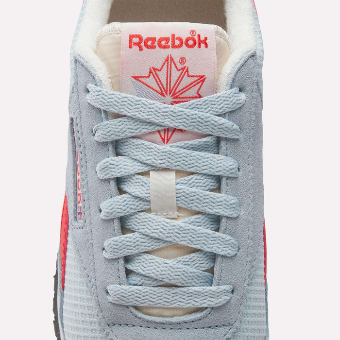 Close-up of Reebok Women's Classic AZ Shoes sneaker with light blue laces, grey and blue mesh, a red star logo on the tongue, and a hint of red on the sides—combining retro running style with modern comfort.