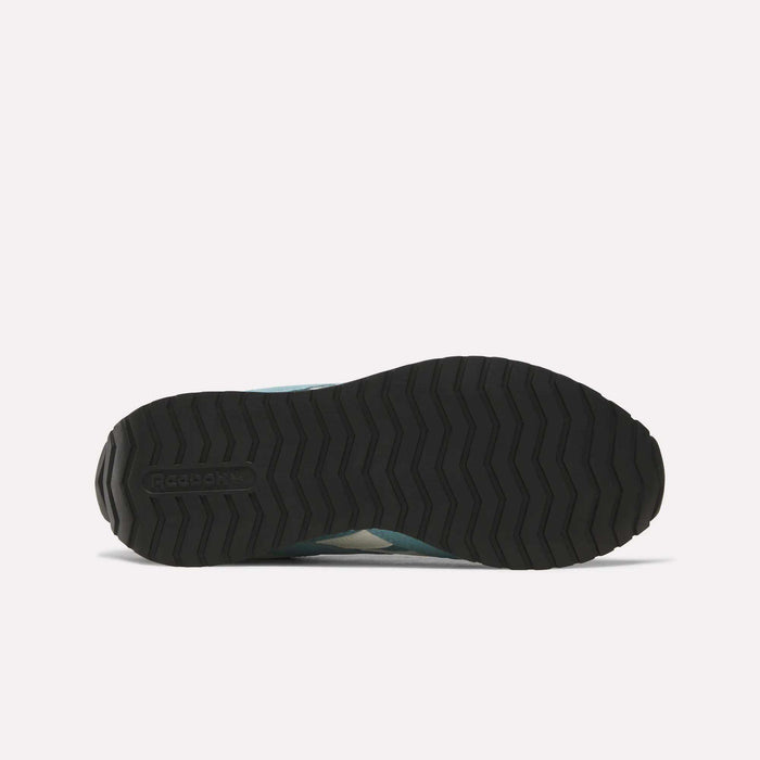 The image displays the black rubber outsole of the Reebok Women’s Classic AZ Shoes, viewed from below, featuring a zigzag tread pattern and the Reebok logo embossed near the heel—an iconic detail characteristic of retro running shoes.