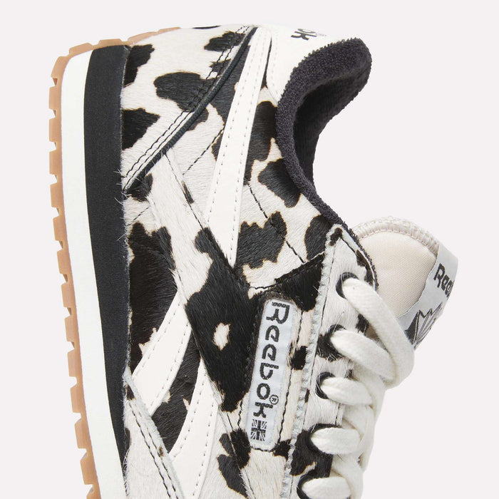 Close-up of Reebok Women's Classic AZ Shoes with a striking black and white animal print, white laces, beige sole, and prominent Reebok logo on the side and tongue.