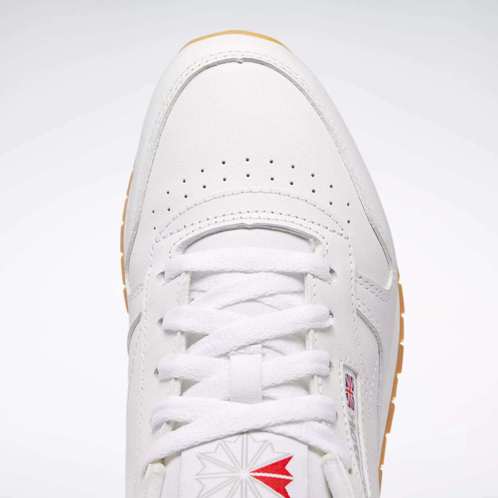 Top view of Reebok Women's Classic Leather Shoes featuring white laces, perforated toe, red and gray star logo near the tongue, small UK flag tag, cushioned midsole for comfort, and a light brown sole at the edge.