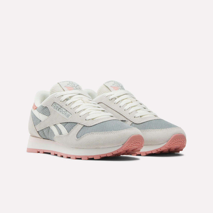 Women's Classic Leather Shoes by Reebok in soft grey, white, and pale pink suede with white laces, pink outsoles, and the Reebok logo on the sides and tongues, shown against a plain light background.