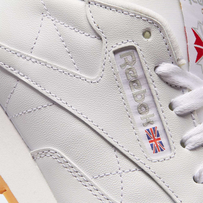 Close-up of Reebok Women's Classic Leather Shoes, highlighting the brand logo, Union Jack patch, white laces, detailed stitching, and cushioned midsole.