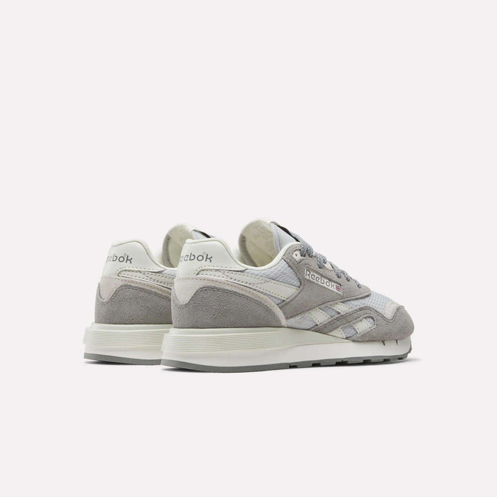 The Reebok Women's Classic Nylon 89 Shoes, shown in grey and white suede and mesh with retro styling, feature the Reebok logo on the heel and side, displayed from back and side angles.