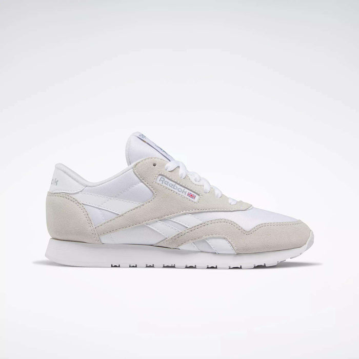The Reebok Women's Classic Nylon Shoes are shown in a side profile, featuring white with beige suede accents, white laces, and a white sole against a light background—versatile sneakers for everyday style.