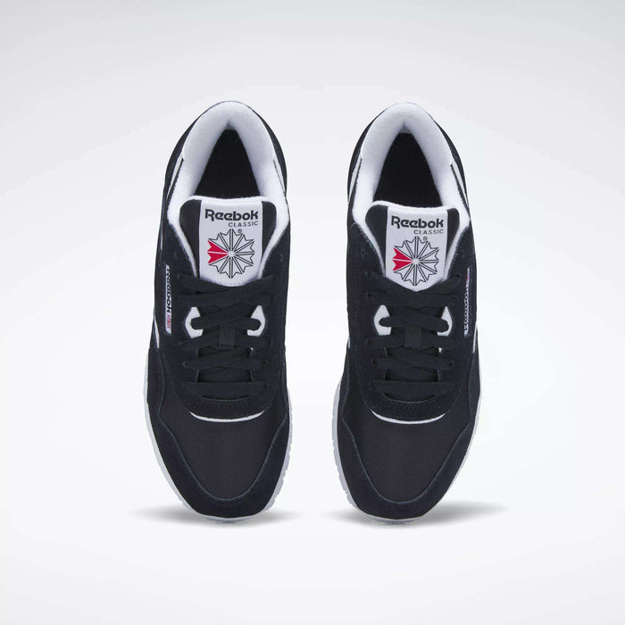 A top view of black Reebok Women's Classic Nylon Shoes with white soles and inner lining, featuring the Reebok logo and a red-and-grey starburst design on the tongue.