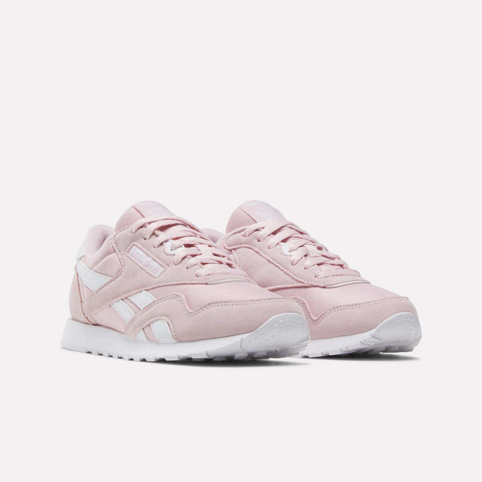 A pair of Women's Classic Nylon Shoes by Reebok in light pink, featuring white soles and white Reebok logo accents, displayed on a plain white background.