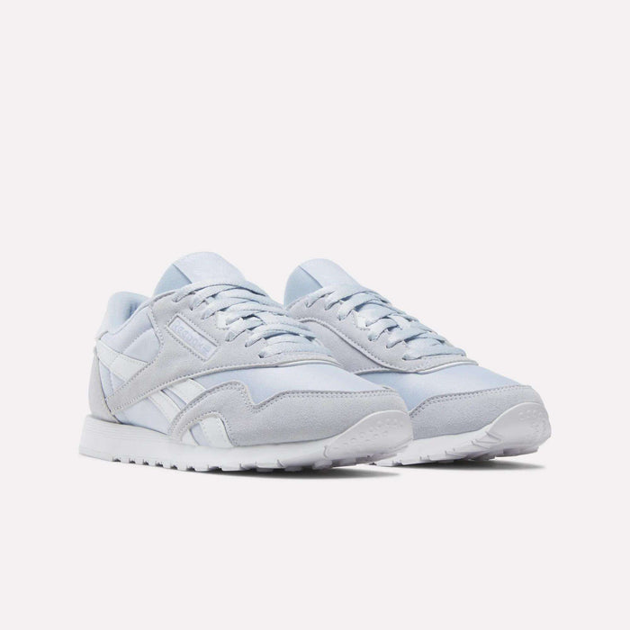 A pair of Reebok Women's Classic Nylon Shoes in light gray and white, featuring suede and mesh accents, white laces, and a white rubber sole, displayed on a plain white background.