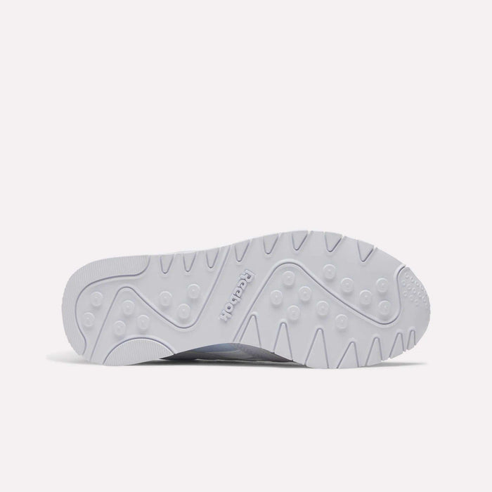 The image displays the white rubber sole of the Reebok Women's Classic Nylon Shoes, featuring circular grips, curved lines, and the embossed Reebok logo at the center—a stylish detail from this classic sneaker.