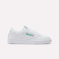 The Women's Club C 85 Shoes by Reebok feature a white low-top design with green branding and a flat rubber sole, displayed in side profile on a plain white background—ideal for women's shoe collections.