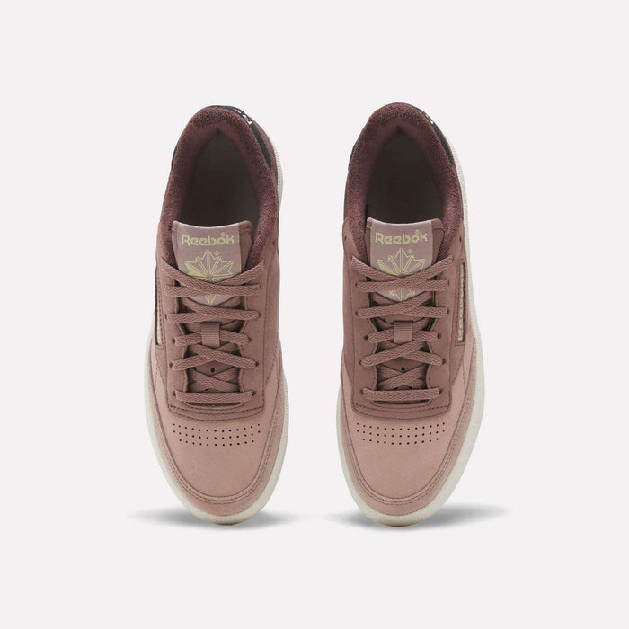A top-down view of the Reebok Women’s Club C 85 Shoes in mauve highlights their coordinating laces, light soles, and gold Reebok logos on the tongues—these fashionable women’s tennis sneakers boast the premium quality and style of nubuck leather.