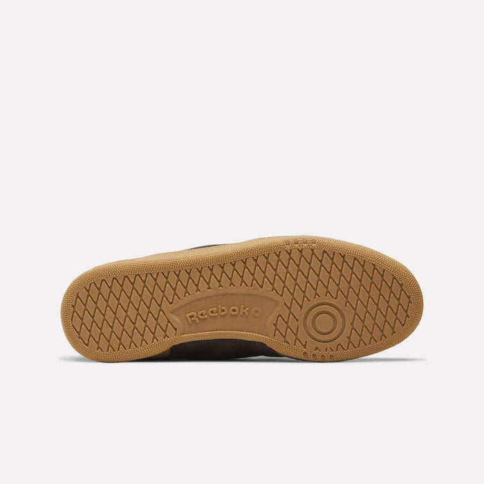 The image shows the gum-colored sole of the Reebok Women's Club C 85 Shoes facing up, featuring a herringbone tread pattern and an embossed Reebok logo in the center.
