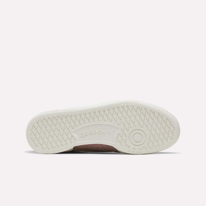The image displays the sole of the Reebok Women’s Club C 85 Shoes, shown horizontally. The white sole has a textured grip pattern and features the Reebok logo at the center.