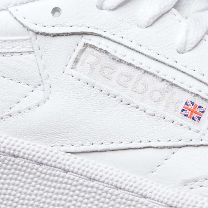 Close-up of the Reebok Women's Club C 85 Shoes highlights the logo, a small UK flag patch, and detailed leather stitching—making these sneakers a timeless choice.