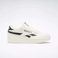 The Reebok Women's Club C Double Revenge Shoes are white with black accents, feature a black Reebok logo and British flag on the side—classic court-inspired style for everyday wear.
