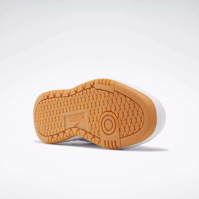 The image shows the sole of the Reebok Women's Club C Double Shoes, featuring a light brown, textured geometric tread pattern with circular grip accents and the Reebok logo at the center.