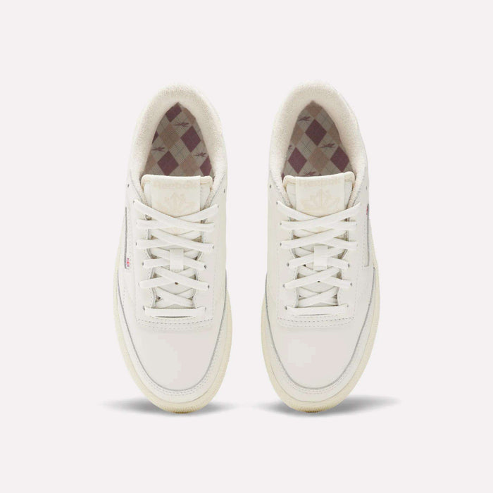 The Reebok Women's Club C Golf Shoes are white, spikeless, lace-up golf shoes with a water-resistant leather upper, minimalist design, and a subtle checkered inner lining.