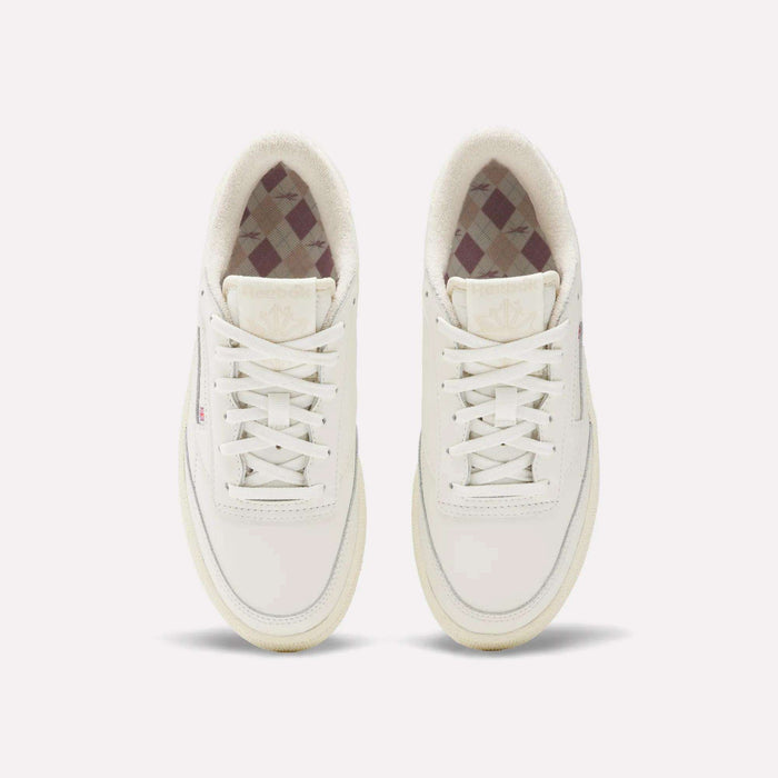 The Reebok Women's Club C Golf Shoes are white, spikeless, lace-up golf shoes with a water-resistant leather upper, minimalist design, and a subtle checkered inner lining.