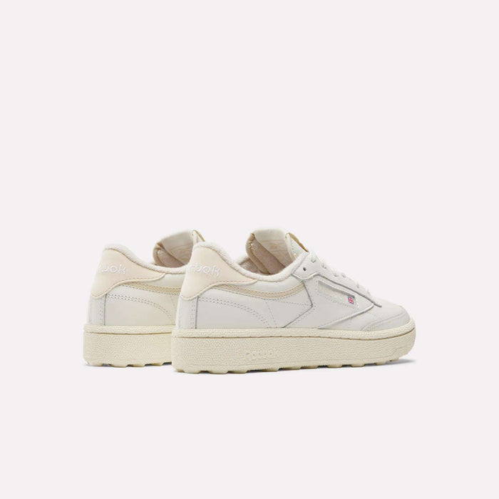 A pair of Reebok Women's Club C Golf Shoes with off-white uppers and beige soles are shown side by side on a white background, displaying the outer and heel views and featuring water-resistant leather for durability.