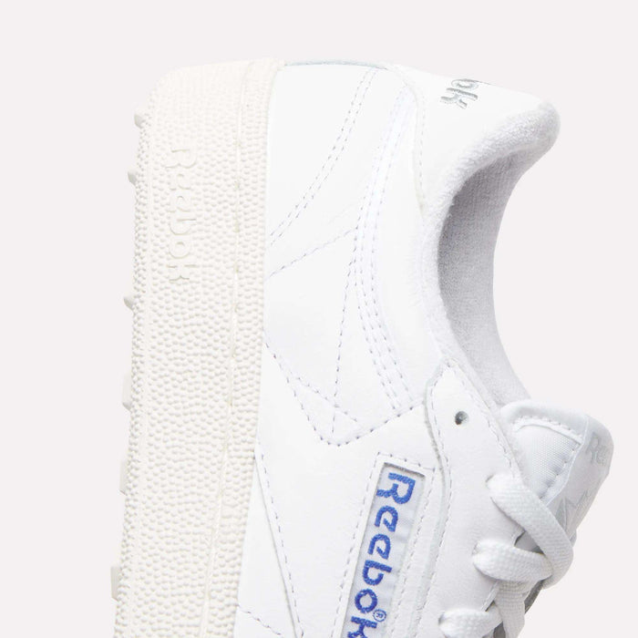 Close-up of Women's Club C Golf Shoes by Reebok, featuring water-resistant leather, spikeless textured sole, side stitching, blue Reebok logo, and white laces set against a plain light background.