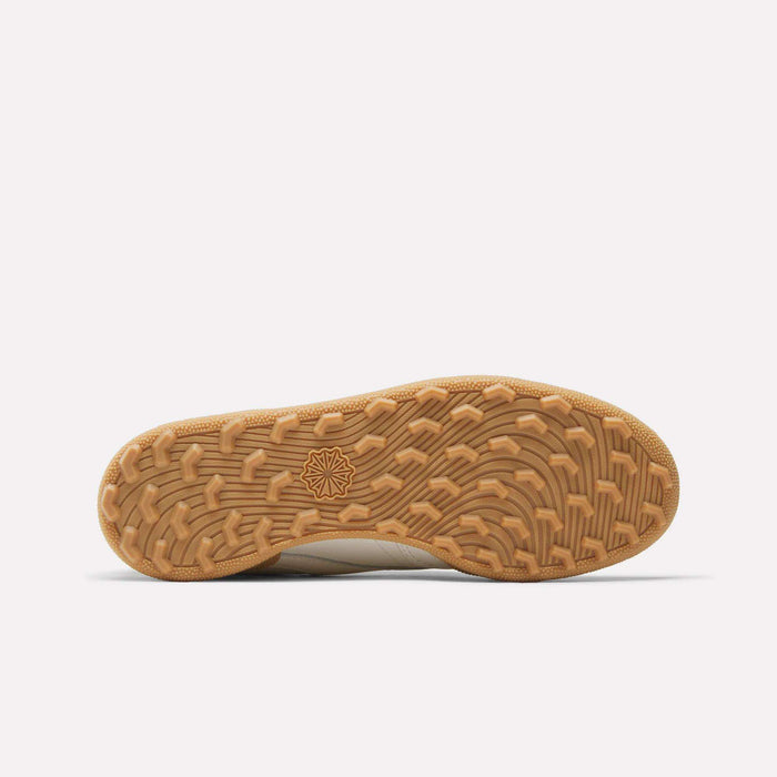 The image displays the underside of Reebok Women's Club C Golf Shoes, featuring a tan spikeless rubber sole with a wavy geometric tread and star-shaped center design, highlighted against a plain white background.
