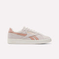 The Reebok Women's Club C Grounds UK Shoes feature a light pink and white suede and leather finish with the Reebok logo and a pink stripe on the side, displayed against a plain white background.