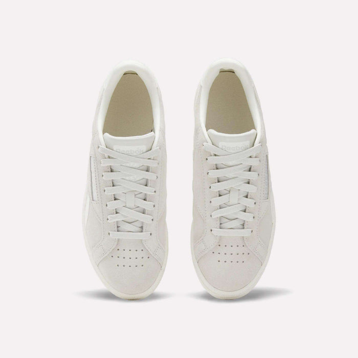 A pair of Women's Club C Grounds UK Shoes by Reebok, shown from above with visible laces and perforated toe on a plain light background—a timeless choice for women’s footwear.