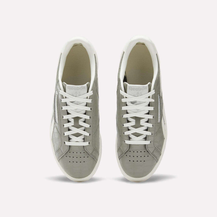 A pair of Reebok Women's Club C Grounds UK shoes in grey with white laces and soles, shown from above on a plain white background. These court-inspired shoes have perforated toes and a clean white inner lining.