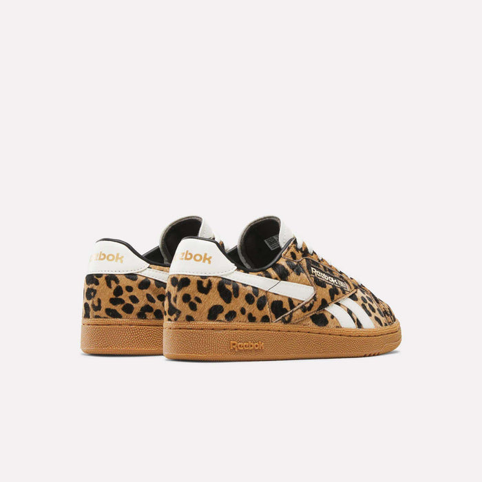 The Reebok Women's Club C Grounds UK Shoes feature a retro design with a brown and black leopard print, white stripes, and gum soles—all showcased against a simple white background.
