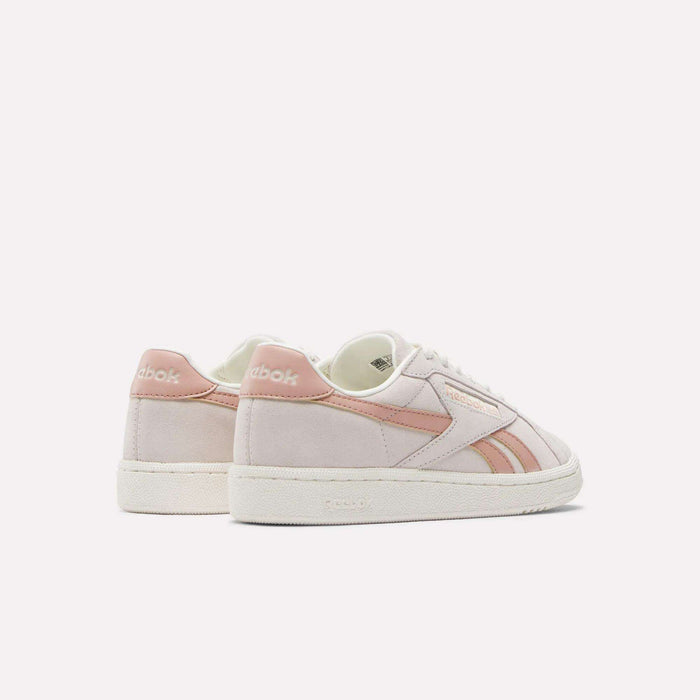 The Reebok Women's Club C Grounds UK Shoes feature light pink and white suede and leather, pink stripe accents, and white rubber soles, shown on a plain white background.