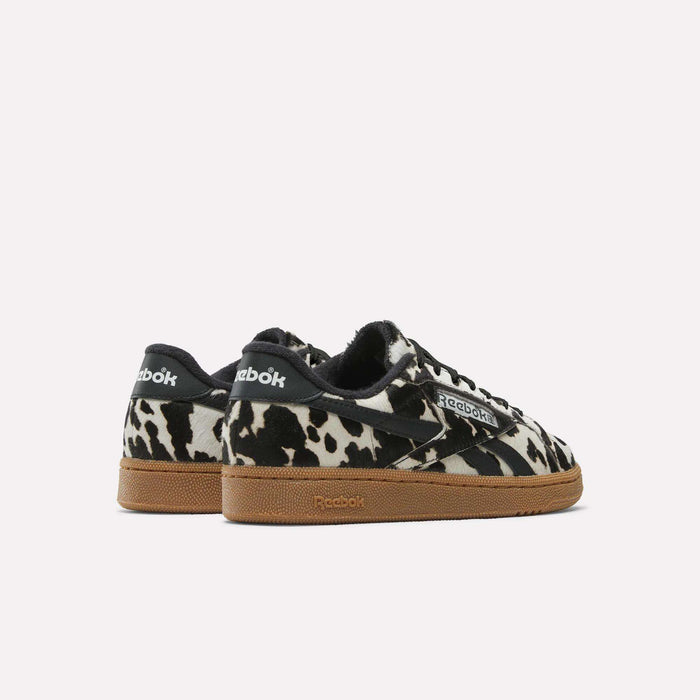 The Women's Club C Grounds UK Shoes by Reebok feature a cow print, black accents, white logos, and brown gum soles—perfect for anyone seeking stylish women's sneakers with a bold twist.
