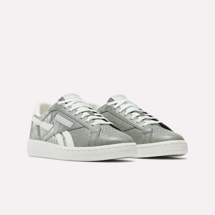 The Reebok Women's Club C Grounds UK Shoes feature a gray leather upper with white soles, laces, and side detailing, shown on a plain white background.