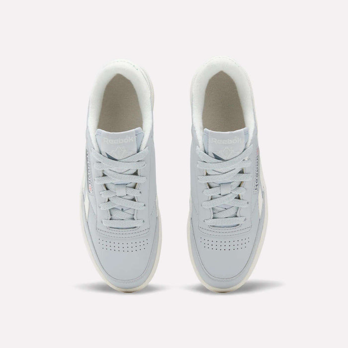 Top view of a pair of Reebok Women's Club C Revenge Shoes in light gray, featuring white soles and laces, placed side by side on a plain background. These casual shoes showcase vintage court style for a timeless look.