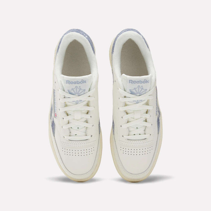 A top view of Reebok Women's Club C Revenge Shoes shows white sneakers with light purple accents, perforated toe boxes, and the Reebok logo with a purple emblem on the tongues.