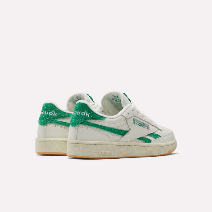 A pair of Reebok Women’s Club C Revenge Shoes in white with green accents and beige soles, displayed from the back and side on a plain white background.