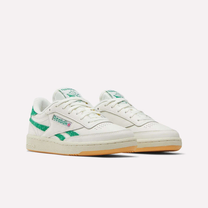 A pair of Reebok Women’s Club C Revenge Shoes in white with green accents and a gum sole, showcased against a plain white background, perfectly capturing the timeless appeal of classic women’s court sneakers.