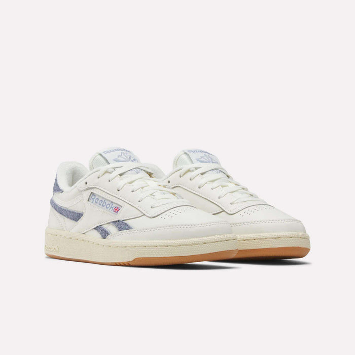A pair of Women's Club C Revenge Shoes by Reebok, featuring white uppers, light beige soles, blue striped accents, and the Reebok logo on the side, displayed against a plain white background.