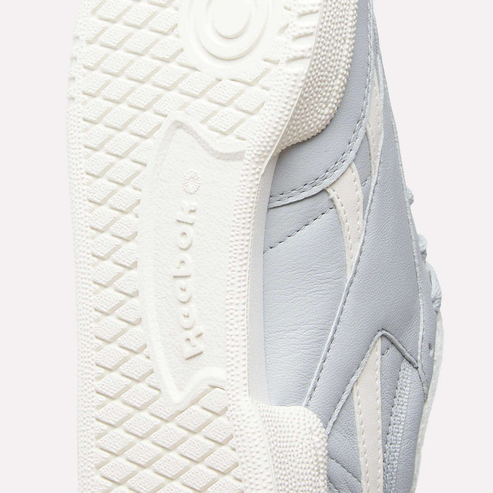 Close-up of the sole and side of a light grey and white Reebok Women's Club C Revenge Shoe, highlighting the textured outsole pattern and a portion of the leather upper for a classic vintage court-inspired look.