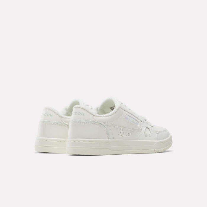 A pair of Women’s Court LXS Shoes by Reebok in white, featuring subtle branding and a full grain leather upper, displayed from the rear on a plain white background.