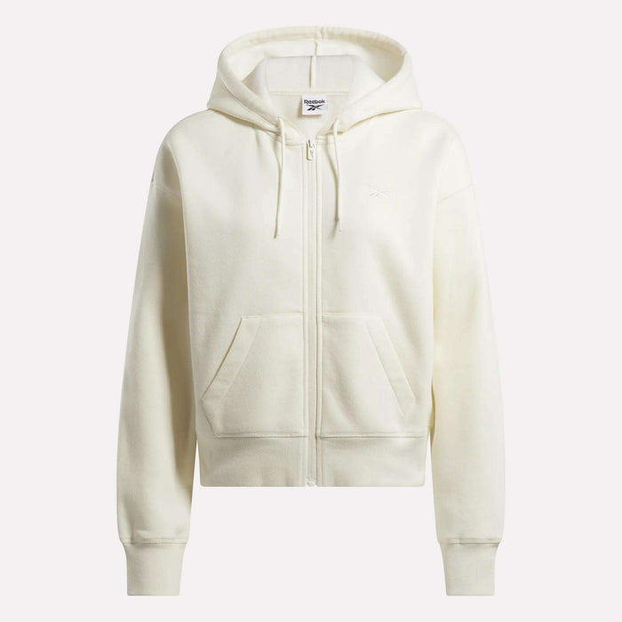 The Women's Cropped Full-Zip Hoodie by Reebok is off-white with a hood, drawstrings, long sleeves, front pockets, and a subtle chest logo. Displayed against a light background.