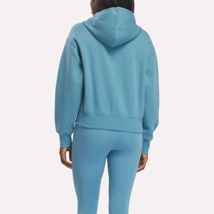 A person is seen from the back wearing a Reebok Women's Cropped Full-Zip Hoodie and matching light blue leggings against a plain white background.