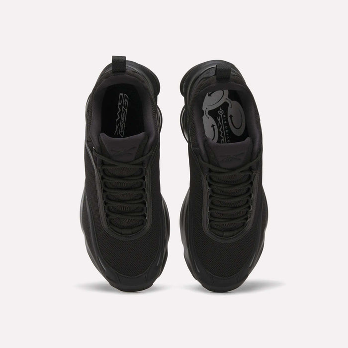 A top-down view of a pair of Reebok Women's DMX Series 3000 Training Shoes in black with mesh uppers, black laces, a patterned black insole, and cushioned design, placed side by side on a light background.