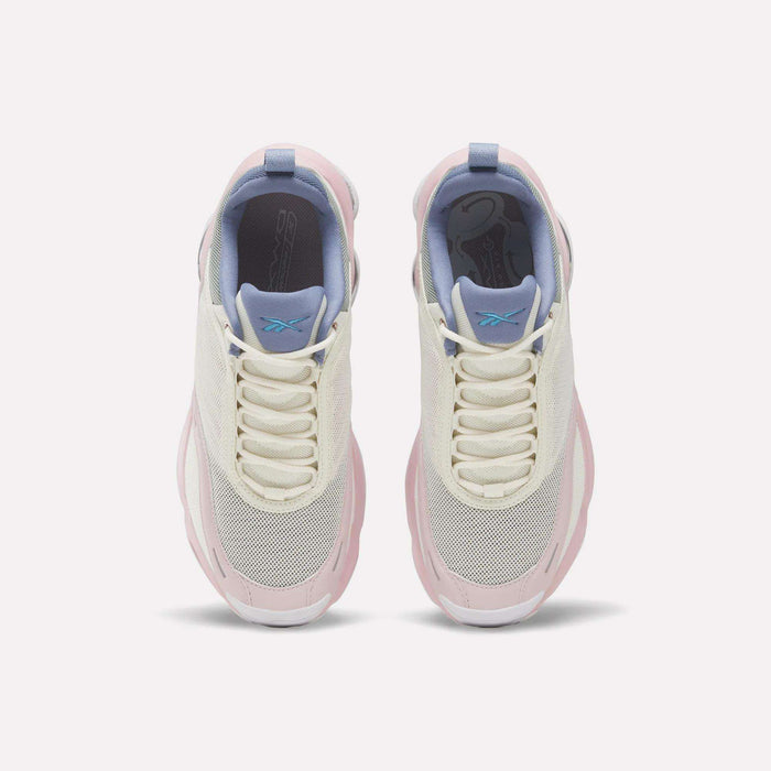 Top view of a pair of Reebok Women's DMX Series 3000 Training Shoes in white, cream, and light pink with mesh toes, lavender tongues, blue pull tabs, and white laces on a plain light background. These cushioned shoes are designed with DMX 3 Technology for superior comfort with every step.