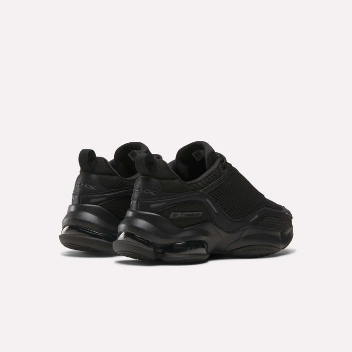 A pair of Reebok Women's DMX Series 3000 Training Shoes in black, with chunky soles, DMX 3 Technology, mesh and synthetic uppers, and subtle branding, shown on a plain light background from the back and side angles.